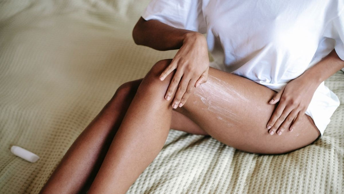 Woman wearing a soft t-shirt applying soothing lotion to her legs after waxing, focusing on calming and hydrating sensitive skin.